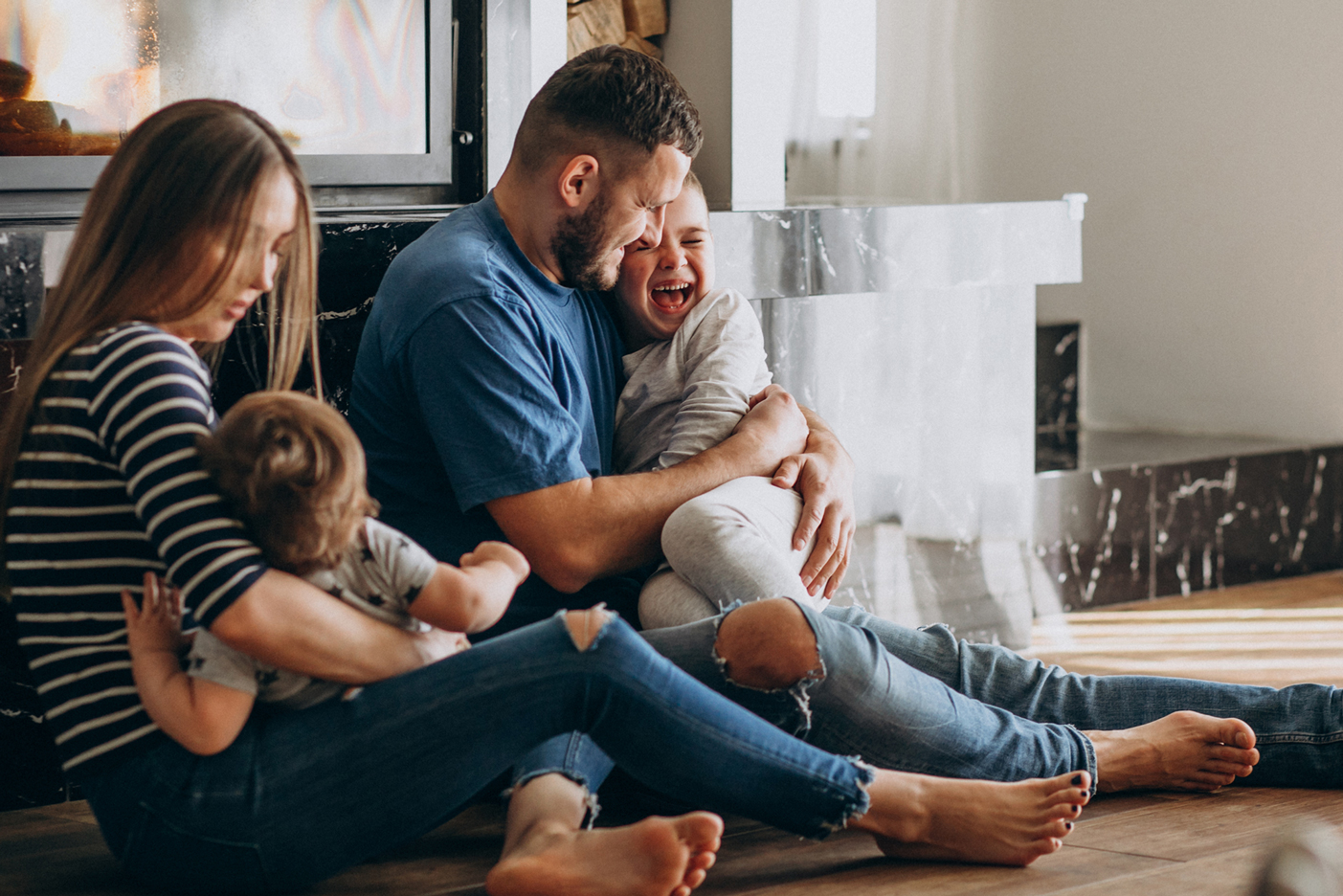 Imagen de una familia riendo sentados en el suelo jugando