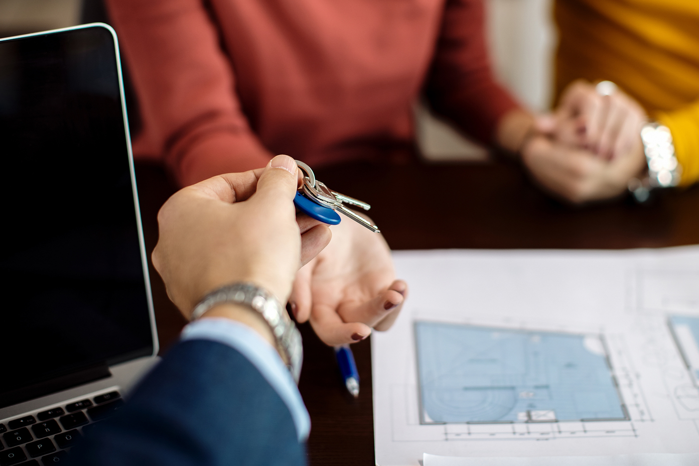 Imagen de una entrega de llaves de una vivienda con las manos entrecruzadas de una pareja que acaba de adquirirla