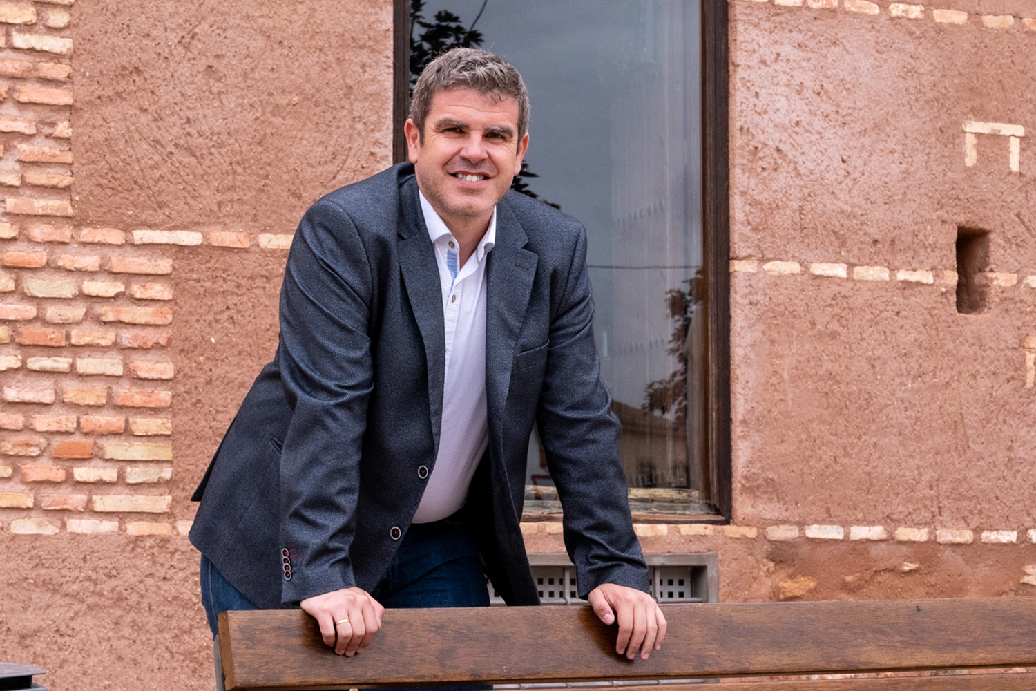 Imagen de Jose Luis de la Torre apoyado en el respaldo de un banco y mirando a cámara y sonriendo